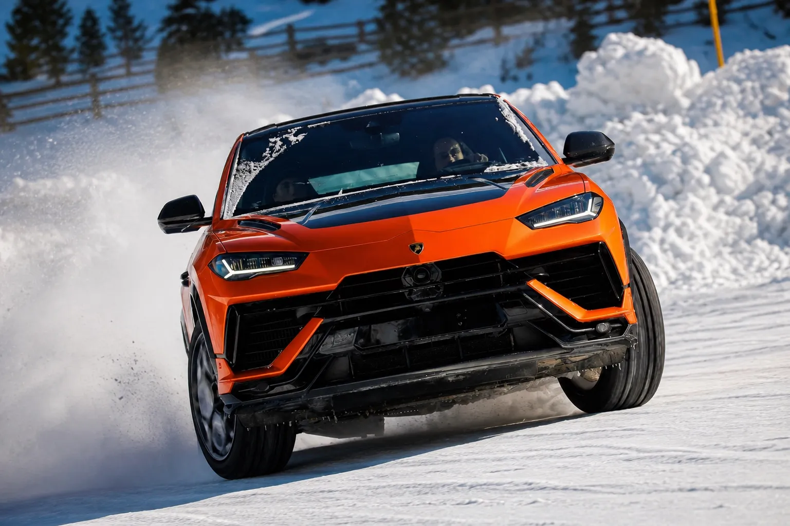 Orange Lamborghini Urus driving on a snowy route